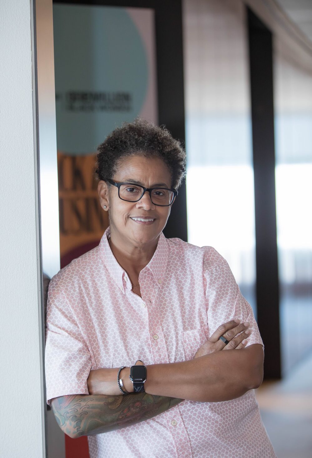 Melissa Bradley, smiling with arms crossed, leaning in an office doorway